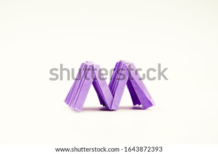Purple letter M origami stands on a white background