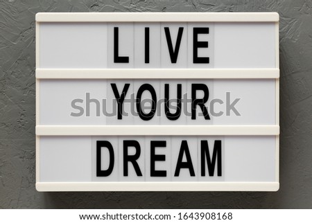 'Live your dream' words on a modern board on a gray background, top view. Overhead, from above, flat lay.