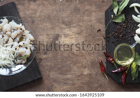 XE salad of freshly salted river pike fish on a cutting kitchen board with ingredients for cooking. Pike fillet pieces. Wooden brown ancient background.