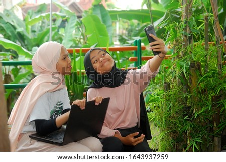 Close up  Muslim womens taking selfies while smiling with smartphones in the park