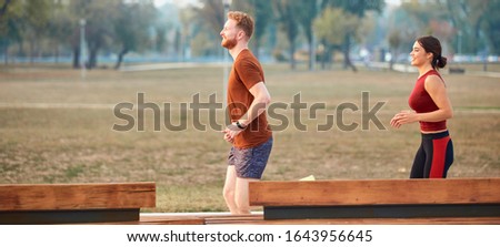 Modern woman and man jogging / exercising in urban park.