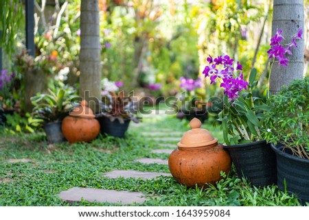 Thai garden decoration with Thai water pot and orchid flower  Royalty-Free Stock Photo #1643959084