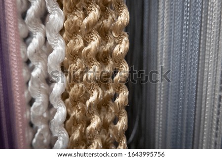 Textile strings and ropes hangs in a fabric shop. Abstract background.