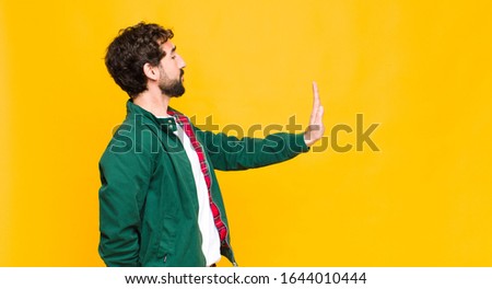 young crazy bearded man against orange wall copy space.