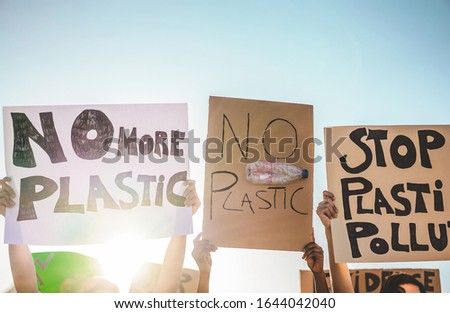 Group of millennials demonstrators on road, young people from different culture and races fight for plastic pollution and climate change - Global warming and enviroment concept - Focus on banners