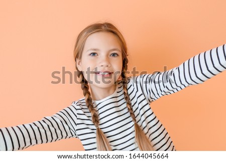 Cute little girl taking selfie on color background