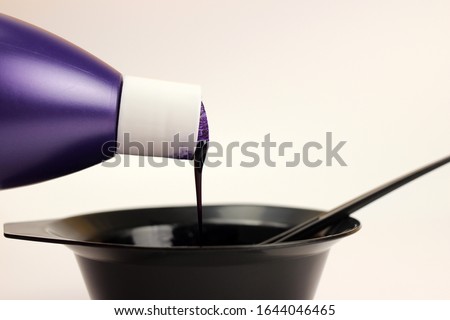 Hair dye is poured from a bottle into a bowl isolated on white Royalty-Free Stock Photo #1644046465