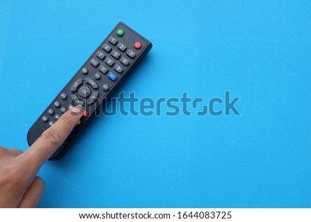 close up Hand holding tv remote isolate on blue background concept of watching tv
