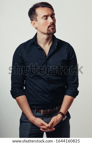 Photo of a handsome man on a bright background in the studio. Vertical photo. The man tries to express his emotions with his expressions.