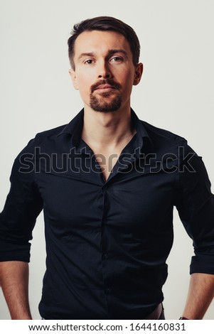 Photo of a handsome man on a bright background in the studio. Vertical photo. The man tries to express his emotions with his expressions.