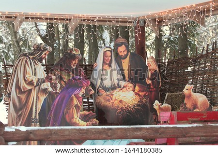 colorful Christmas nativity scene decorated with a luminous garland, a scene of the birth of Jesus. Stock photo with empty space for text.