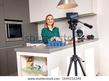 Young woman recording vlog at home in the kitchen preparing dough for pasta.