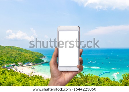 hand holding white smartphone background is the Sea beach and blue sky from "Koh larn" in pattaya ,Thailand. Traveling Thailand.