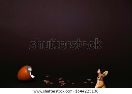 Easter egg, eggshell and bunny on dark background with copyspace. Banner of moody minimalistic decoration concept. Stock photo.