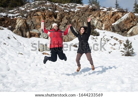 Two young happy teenage girls jumping with pleasure at snow. Troodos mountains Cyprus.