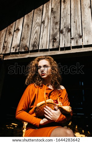 Portrait of woman with curly hair holding a corns cobs in a wooden plate. 