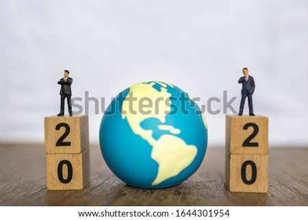 2020 New year , Global and Business concept. Close up two businessman miniature figure people standing on top of stack of wooden number block and mini world toy ball with copy space