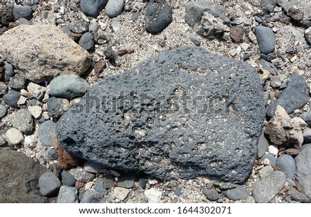 Big gray stone in the sand on the seashore, gray textured background.