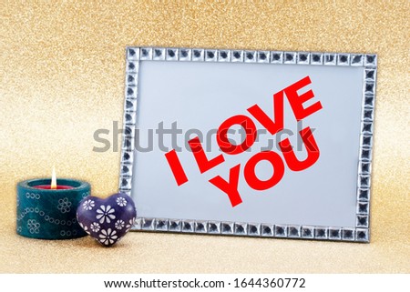 Candle light and a picture frame with the text I LOVE YOU on golden background