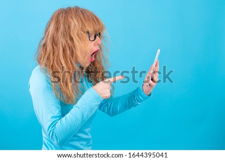 adult or senior woman with smart phone isolated on blue background