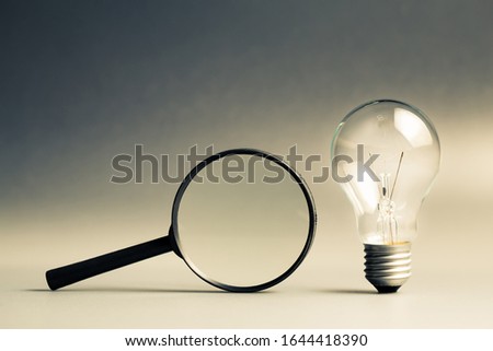 Glowing light bulb with magnifying glass, searching creative idea, tips and tricks