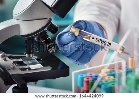 microbiologist with a tube of biological sample contaminated by Coronavirus with label Covid-19 / doctor in the laboratory with a biological tube for analysis and sampling of Covid-19 infectious disea Royalty-Free Stock Photo #1644424099