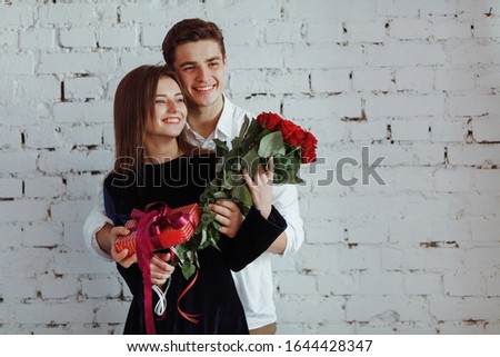 A guy and a girl celebrate a holiday on March 8, They are cheerful and happy on a women's day. The guy gives the girl flowers and gifts

