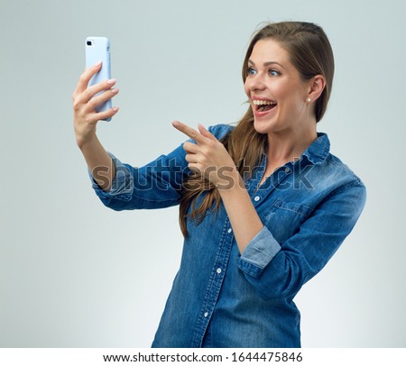 Happy woman wearing casual making self photo with smartphone and pointing finger. isolated female portrait.