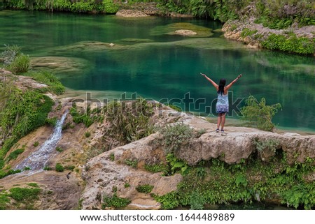 woman standing over the rock stretching her hands and enjoying the waterfall, waterfall in (EL SALTO-EL MECO) san luis potosi Mexico