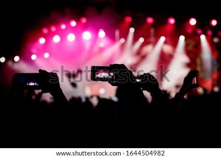 Silhouette of hands using smartphones to take pictures and videos at live music show