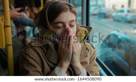 Sick young woman coughs sneezes on the tram cold autumn day flu season disease fever grippe health illness infection influenza migraine sickness slow motion Royalty-Free Stock Photo #1644508090