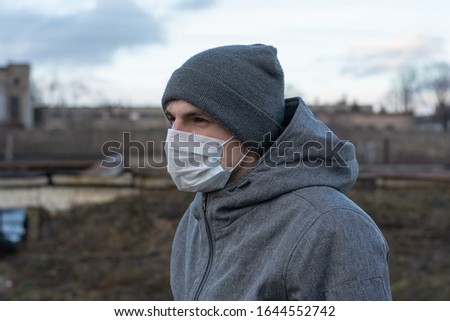 men on the outskirts of the city. standing in profile. on the face is a white rag disposable mask. protection against coronavirus. medical safe means of protection against diseases and viruses.
 Royalty-Free Stock Photo #1644552742