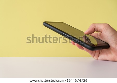 People hand using smartphone with blank yellow clear background. Business, financial, trade stock maket and social network concept.