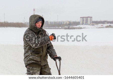 Worker with iron tongs captures on the ice of a frozen river