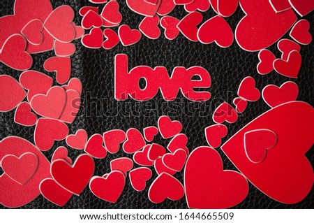 Valentine's Day background. Colorful red hearts and word love on black leather background