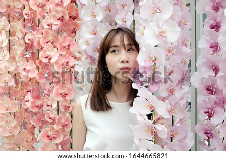 Portrait of an asian female woman with a pastel flower backdrop in Bangkok, Thailand.
