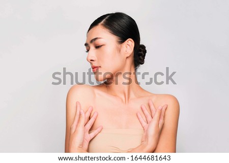 young beautiful asian woman with clean and bright skin, Cosmetic Beauty Concept,hands touch on the cheek on grey background