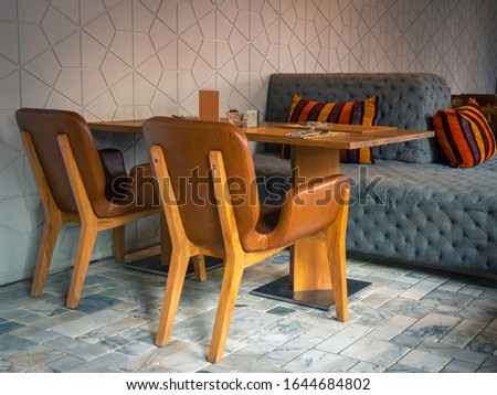 Empty interior of a small cafe, there is a seating area with leather sofas and a wooden table.