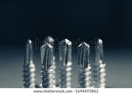 Tapping screw made of steel on the dark rustic background. Selective focus. Shallow depth of field. Black and white image.