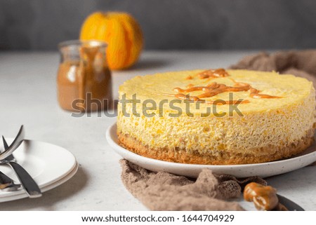 Pumpkin cheesecake with caramel sauce, light grey stone background. Selective focus. 