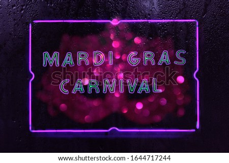 Neon Mardi Gras Carnival Sign in Rainy Window