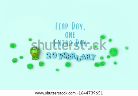 text "Leap day, one extra day", February 29 date, decorative fluffy balls and toy Frog on abstract green background. leap day, leap year concept. 