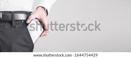 Man putting smartphone in pocket of trousers.