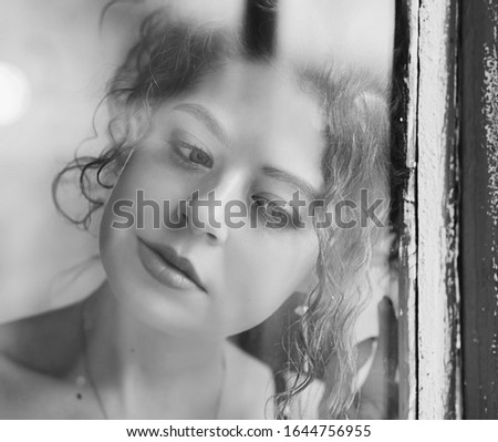 Portrait of a young calm woman in window. 