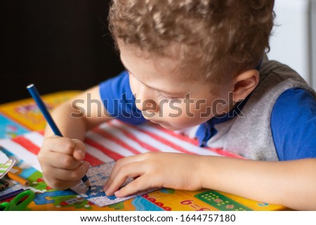 Little boy draws a USA flag. The boy colors the flag with crayons. Education, the study of state symbols.