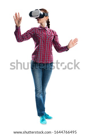 Young woman exploring virtual world, interacting with digital interface. Lady wearing VR goggles and gesturing in air. Studio photo by side view girl against gray background. Cyber technology concept