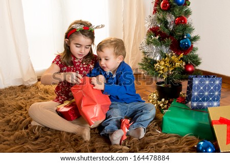 Cute little kids on rug opening Christmas Presents