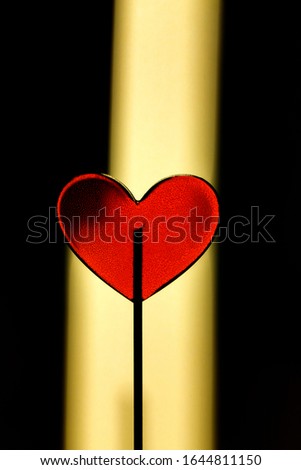 red heart as lollipop candy on yellow and black background. Valentines day minimalist background. love symbol, space for text concept. design element for greeting cards, sale selective focus