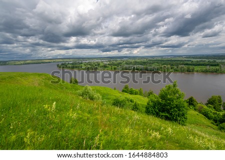 Summer landscape, a large full-flowing river, meadow flowers on the banks of the river, mighty clouds in the sky, a tourist walk along the Kama River