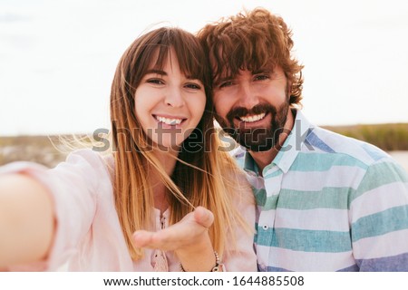 Couple On Beach Summer Vacation, Beautiful Young Happy People Taking Selfie Photo, Man Woman Embrace Sea Ocean Holiday Travel.Happy couple taking a photo on a beach on holidays